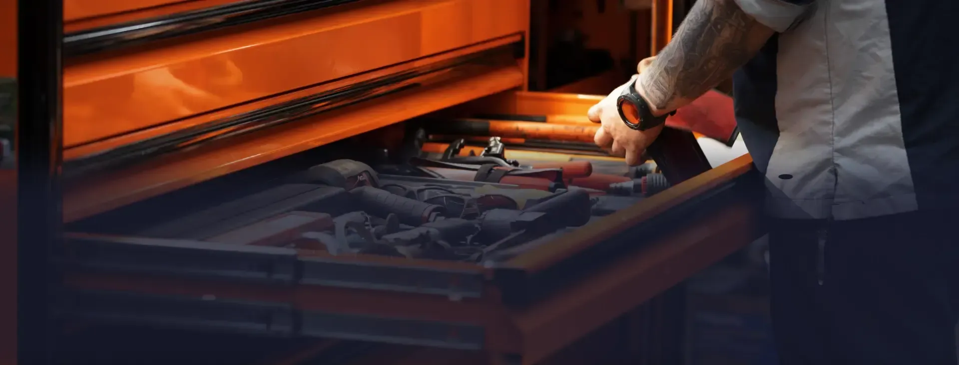 Person reaching into an orange toolbox, looking for a tool.