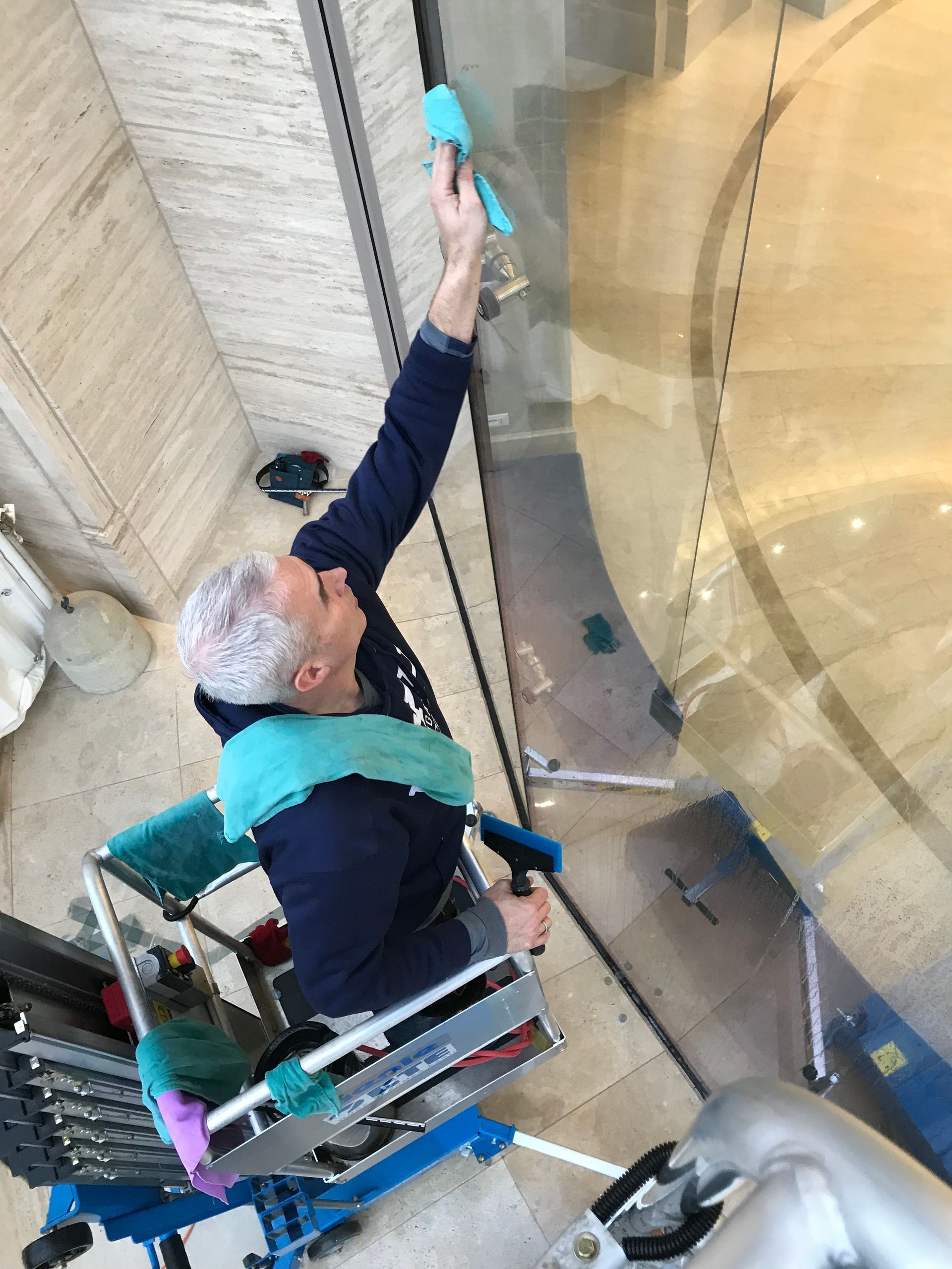 A man in a wheelchair is cleaning a glass door.