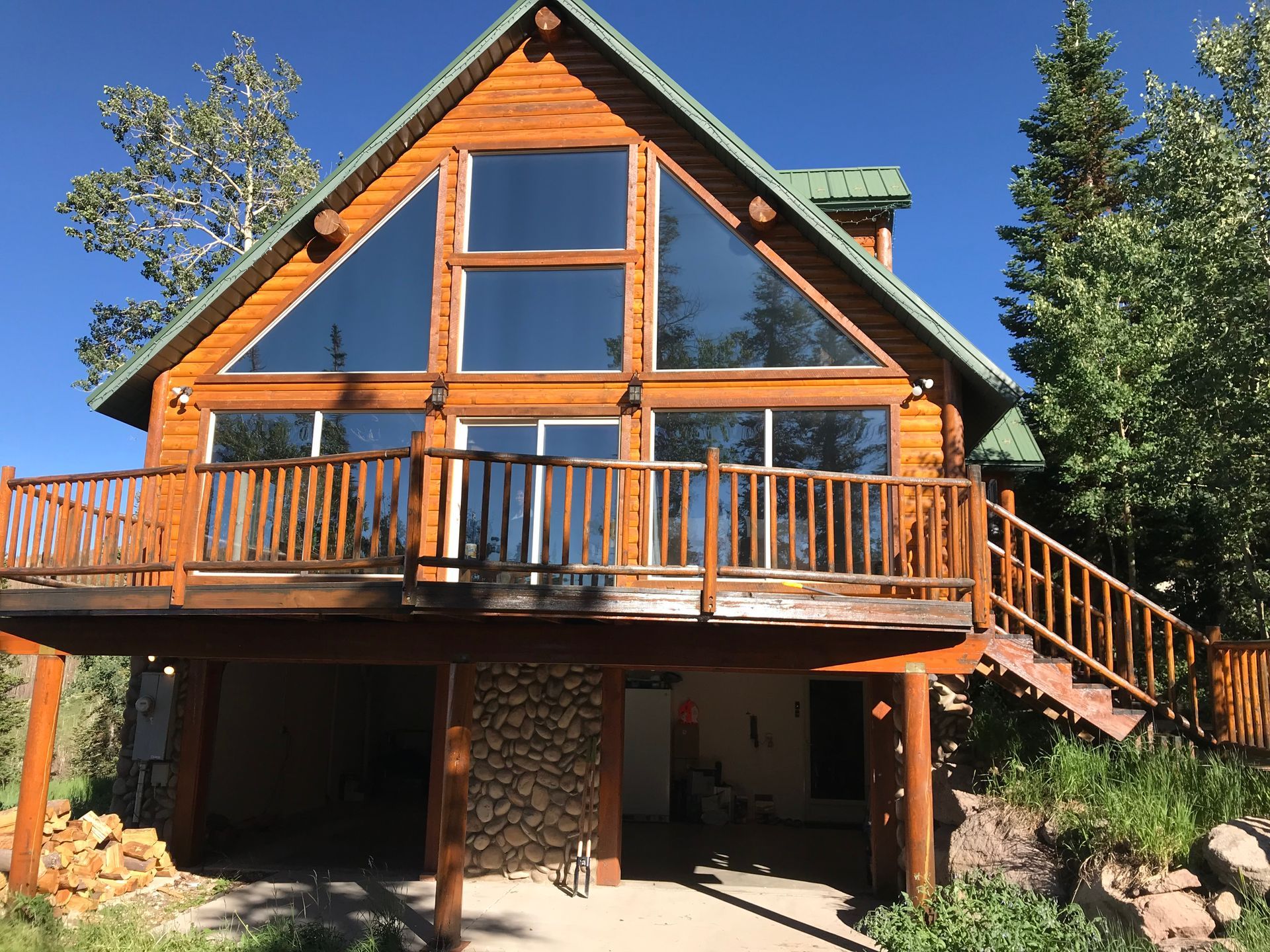 A large log cabin with a green roof and lots of windows