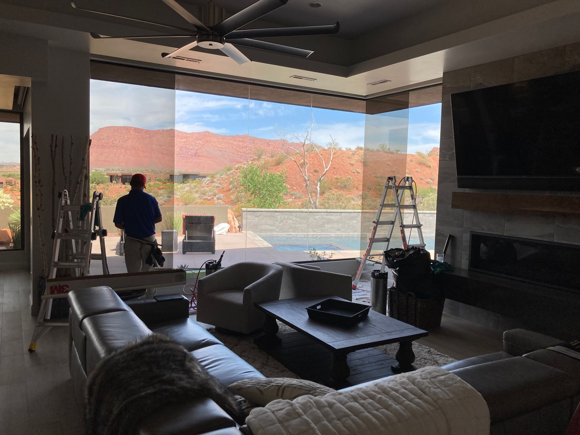 A living room with a lot of furniture and a man standing in front of a large window.