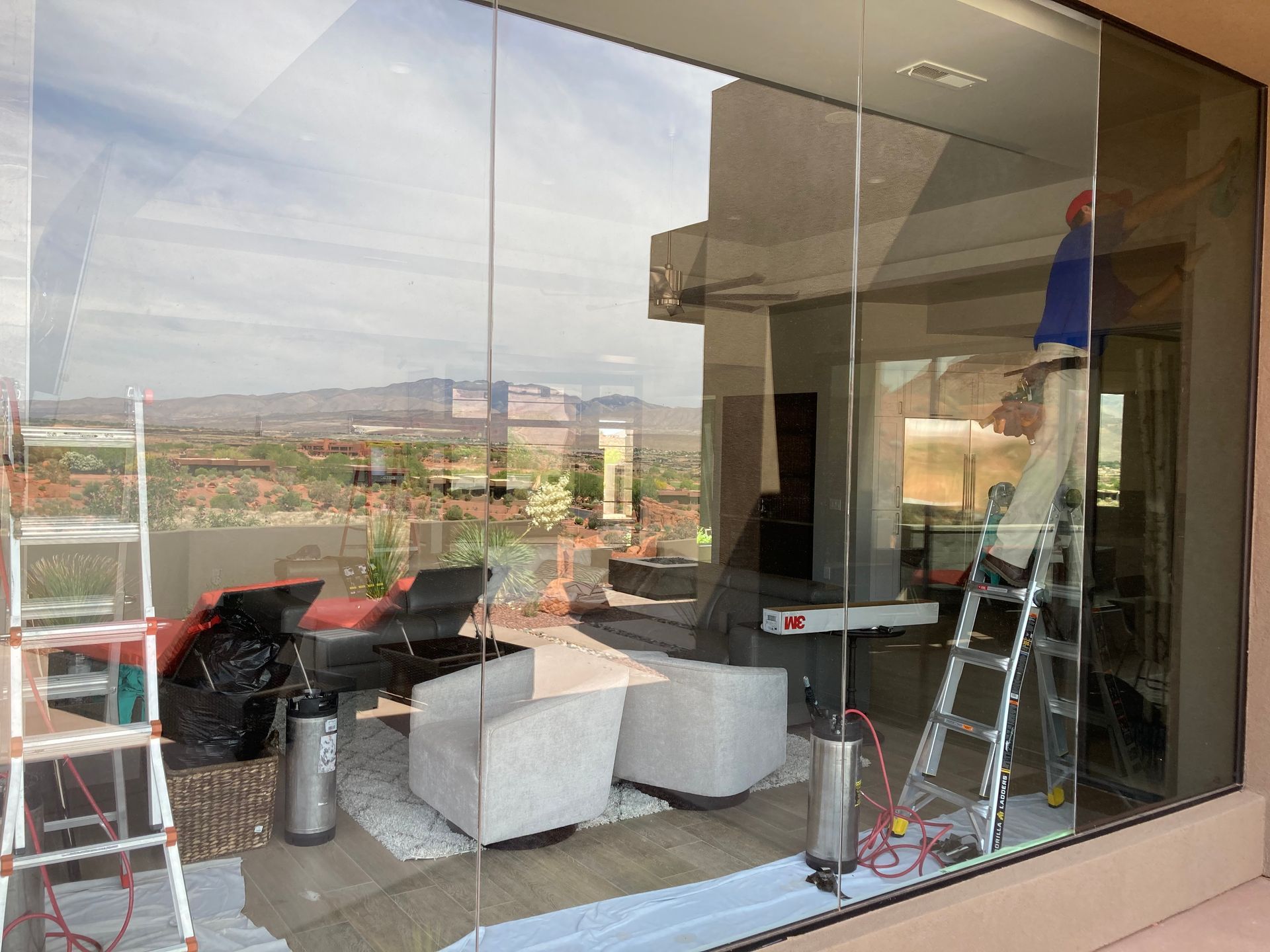 A man is standing in front of a large glass window in a living room.