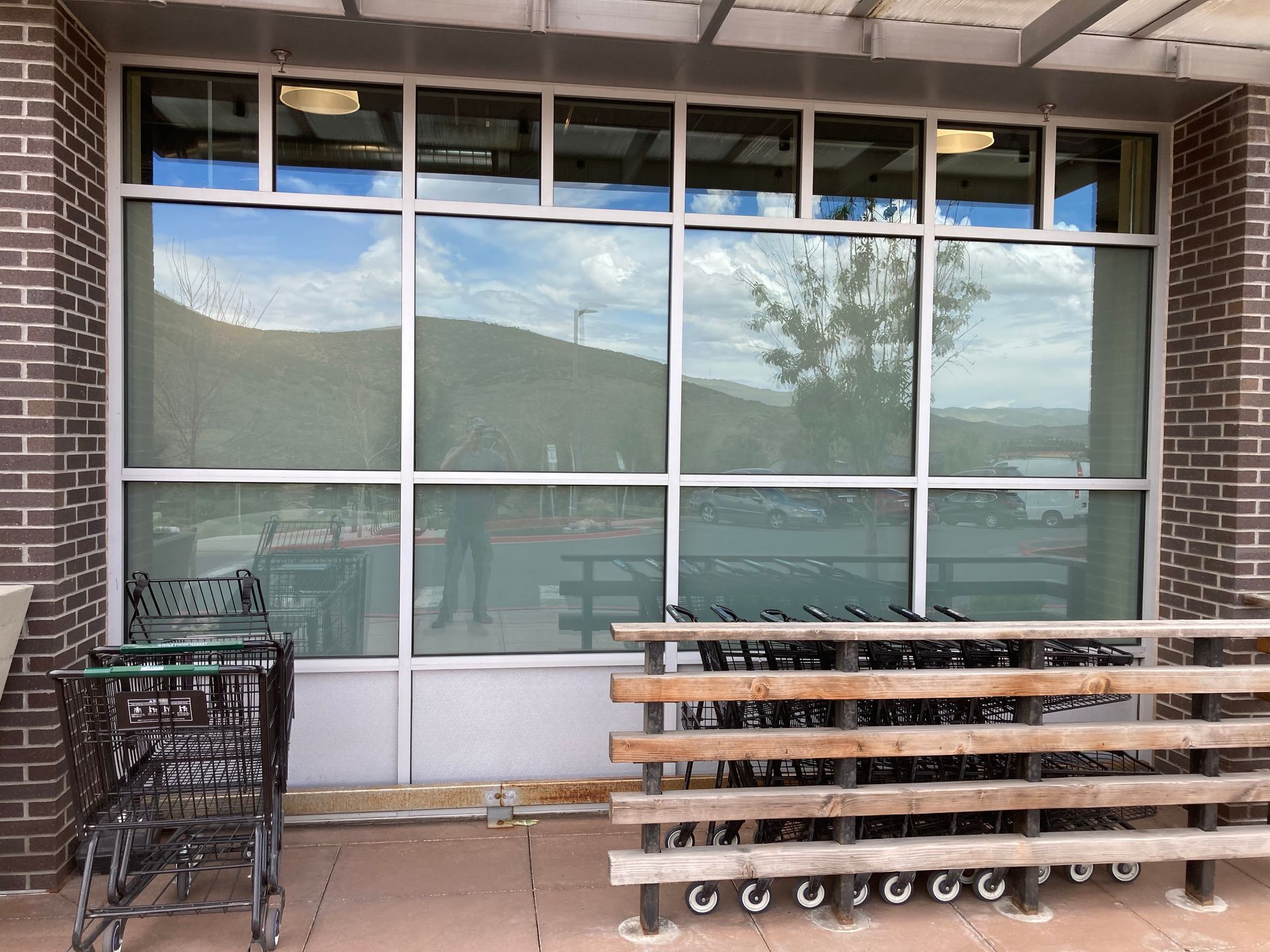 A row of shopping carts are parked in front of a large window.
