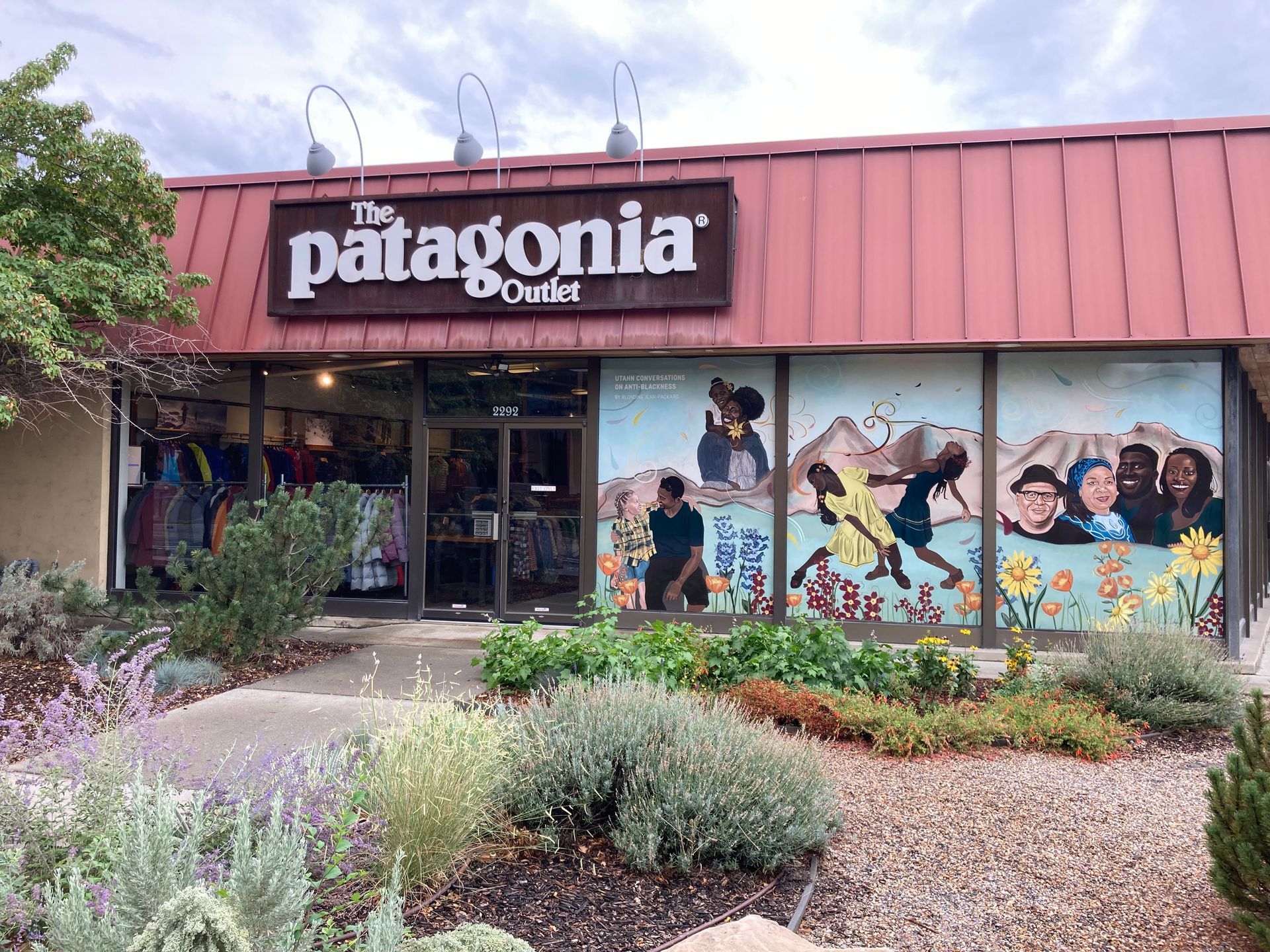 The front of a patagonia outlet store with a mural on the windows.