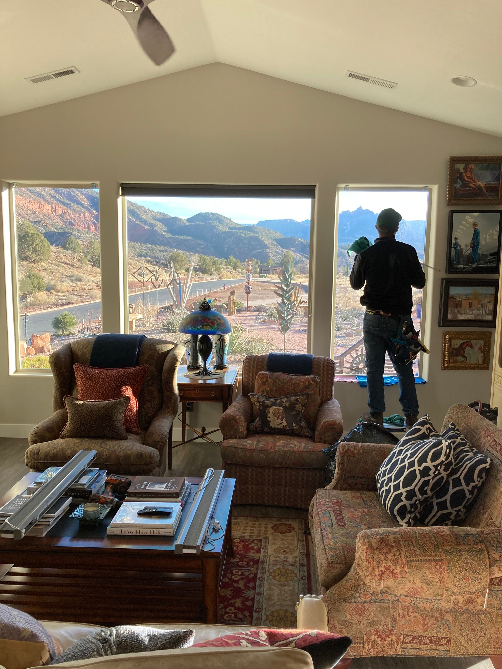 A man is standing in a living room looking out a window.