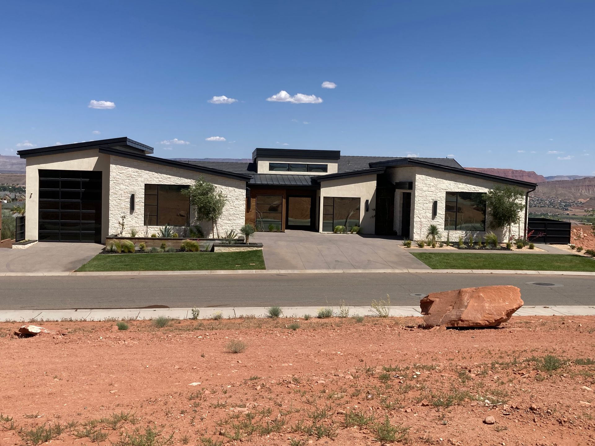 A large house is sitting on top of a dirt field next to a road.