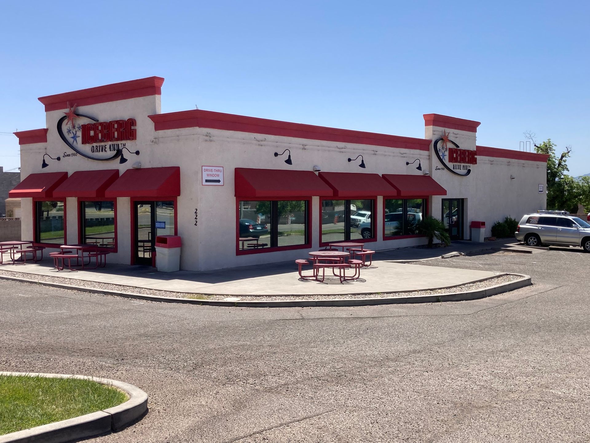 A white building with red awnings and a picnic table in front of it