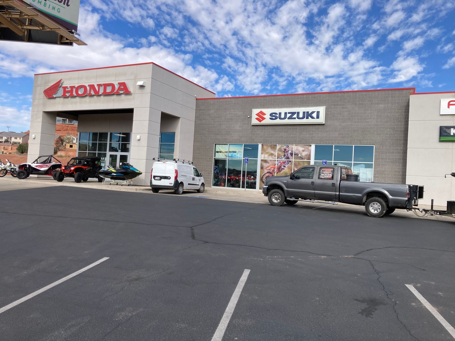 A honda and suzuki dealership with a truck parked in front of it.