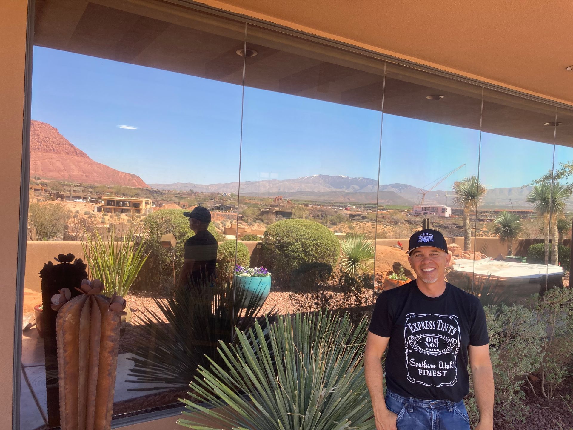 A man standing in front of a window with mountains in the background