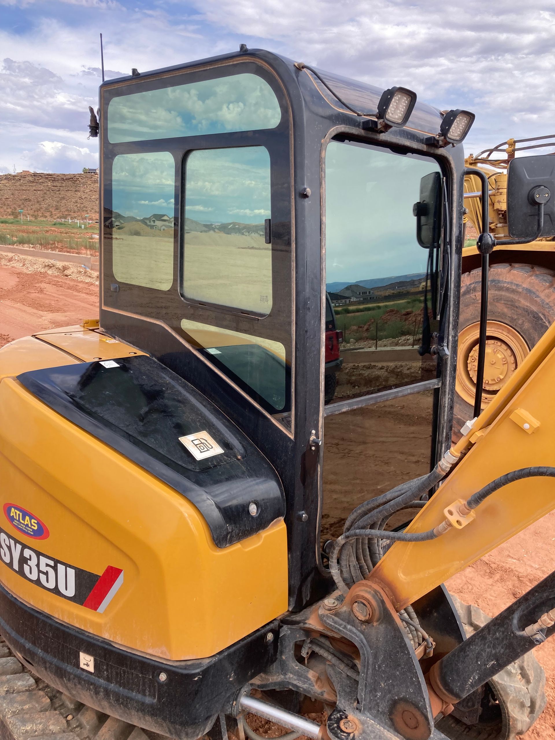 A yellow and black excavator is parked in a dirt field.