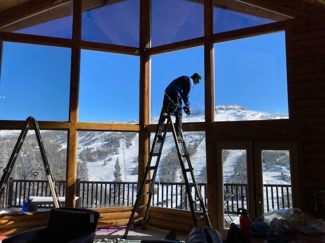 A man on a ladder cleaning a large window