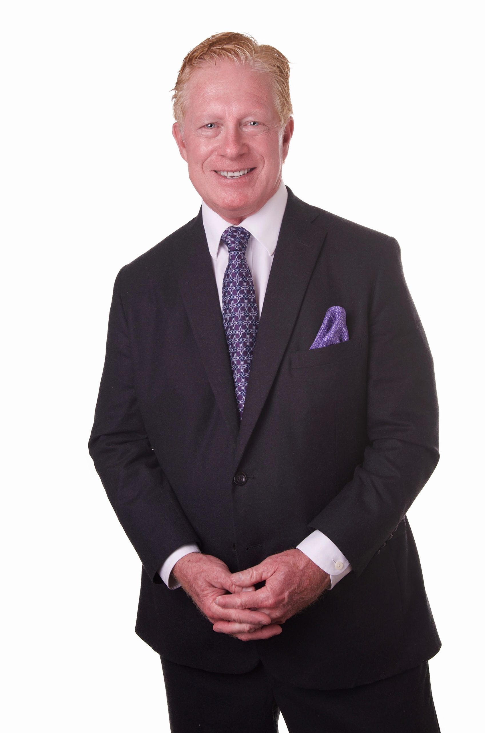 A man in a suit and tie is smiling for the camera