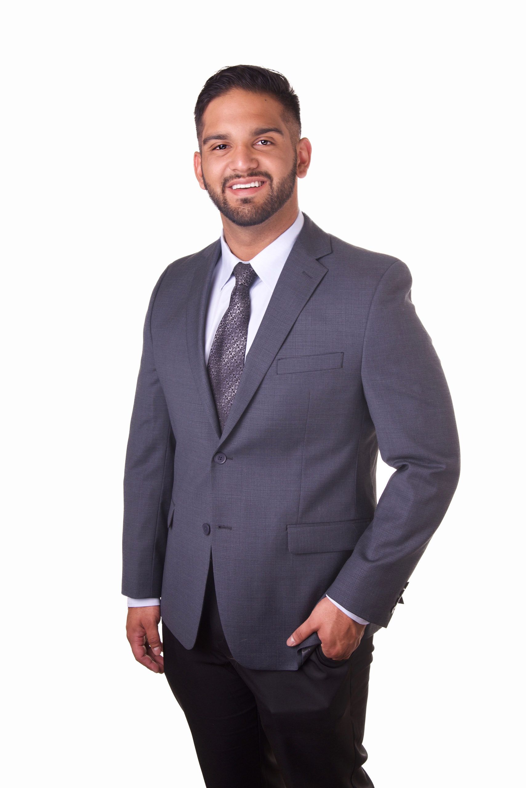 A man in a suit and tie is standing in front of a white background.