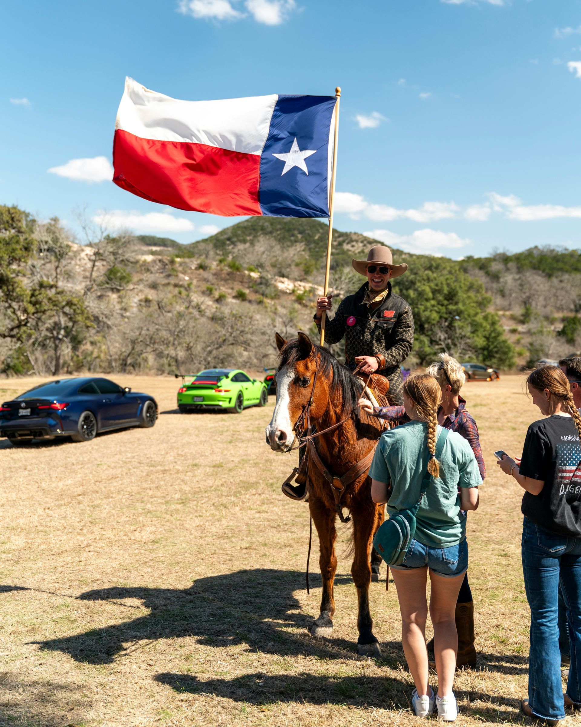 A man is riding a horse while holding a texas flag.
