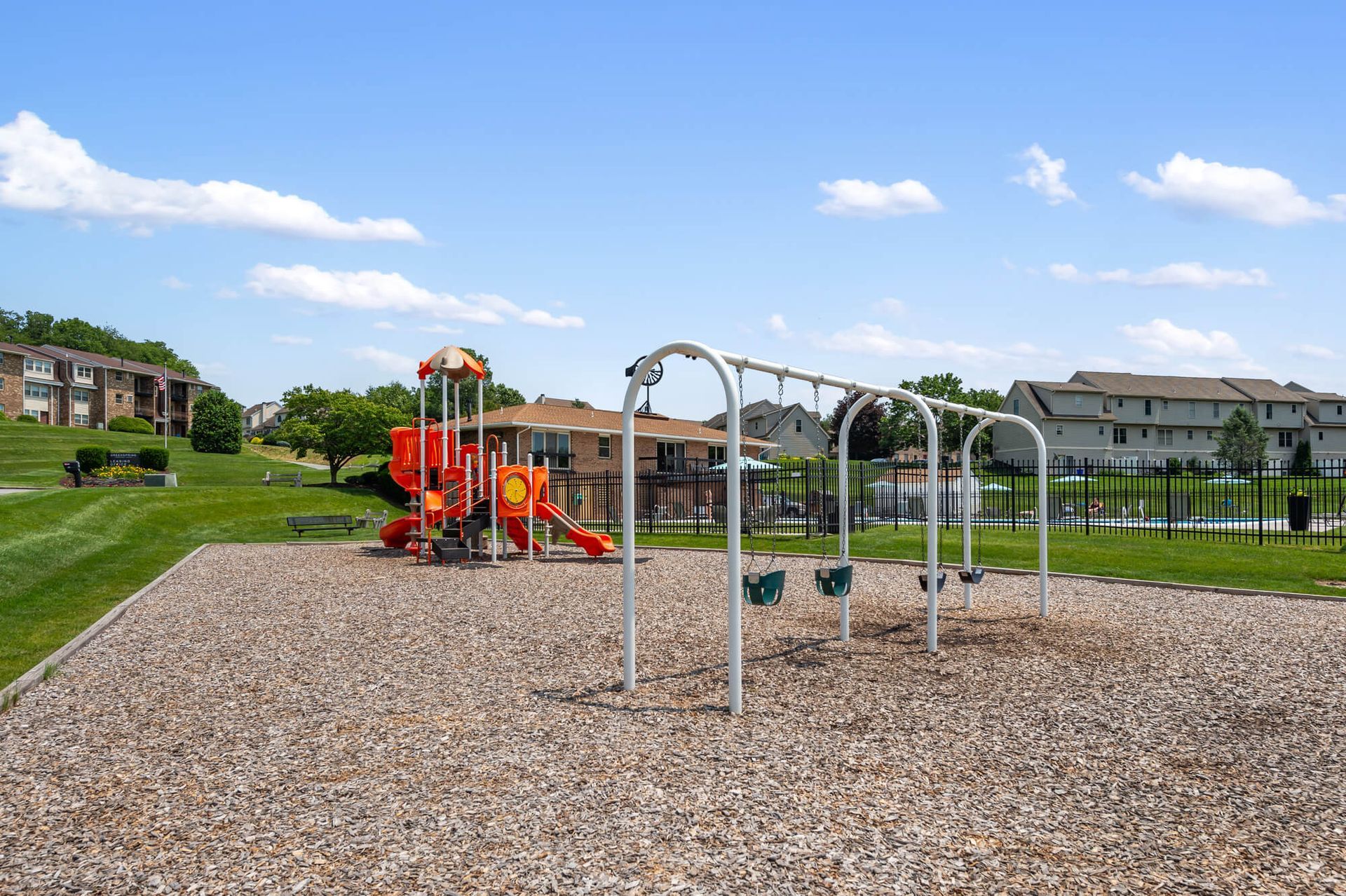 Playground with swings and a bright red slide in a residential community.
