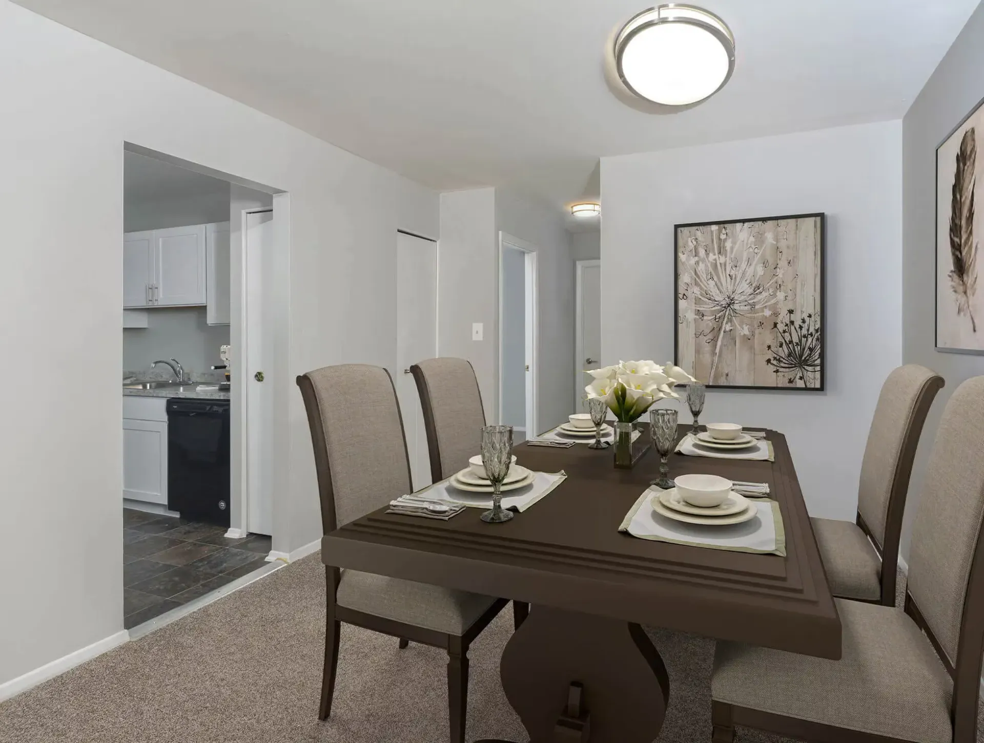 Dining area with a dark wood table, beige upholstered chairs, and wall art in a modern apartment.