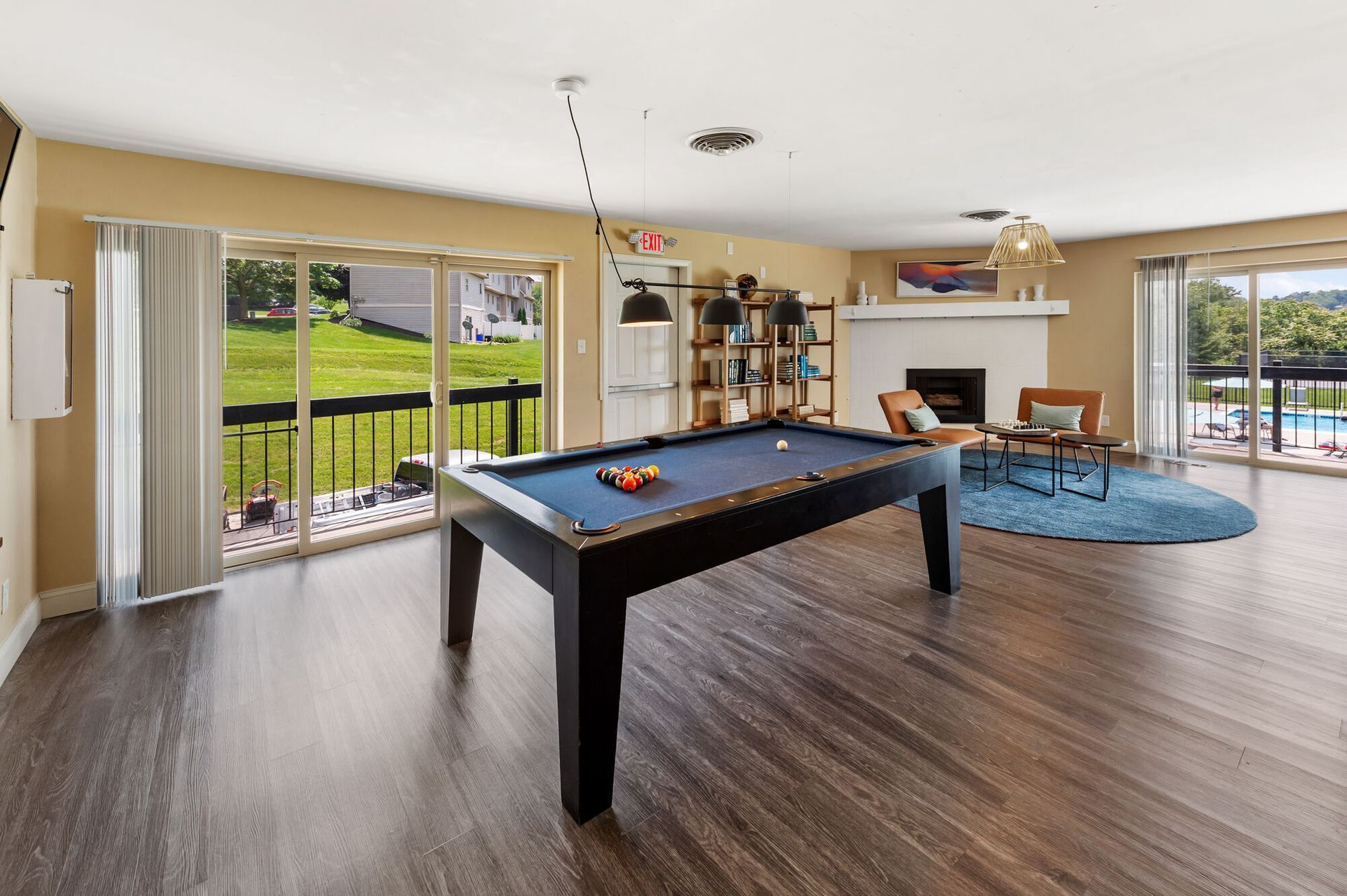 Spacious community game room with a pool table, seating area, and a fireplace.