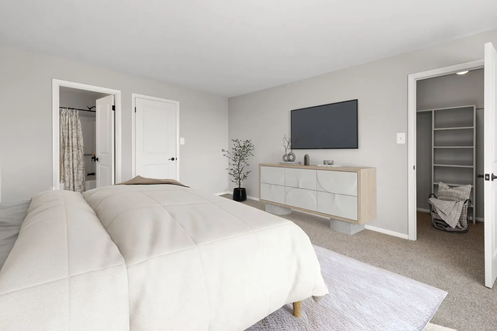 Bedroom with a large bed, beige comforter, dresser with a mounted TV, and an open closet.