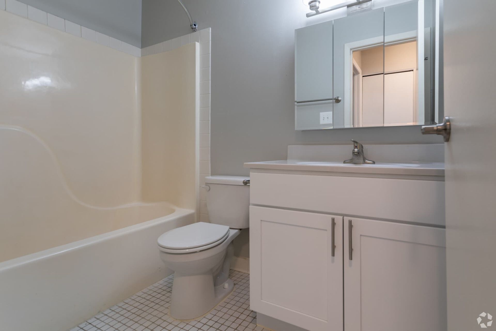 Bathroom in an apartment unit with a tub/shower, toilet, and white vanity.