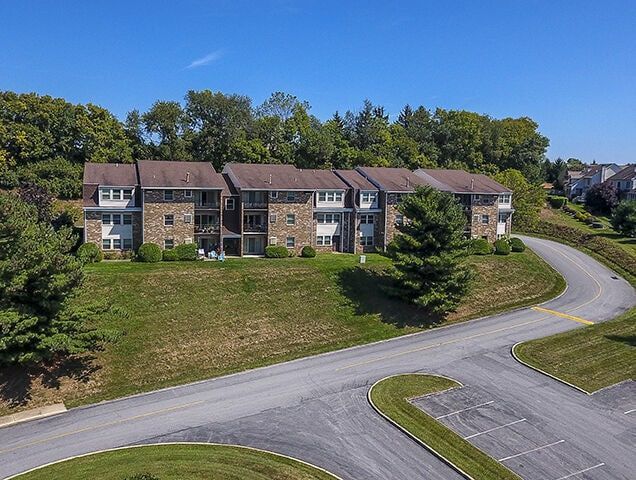 Exterior view of a brick apartment complex with curved driveway and manicured lawn.