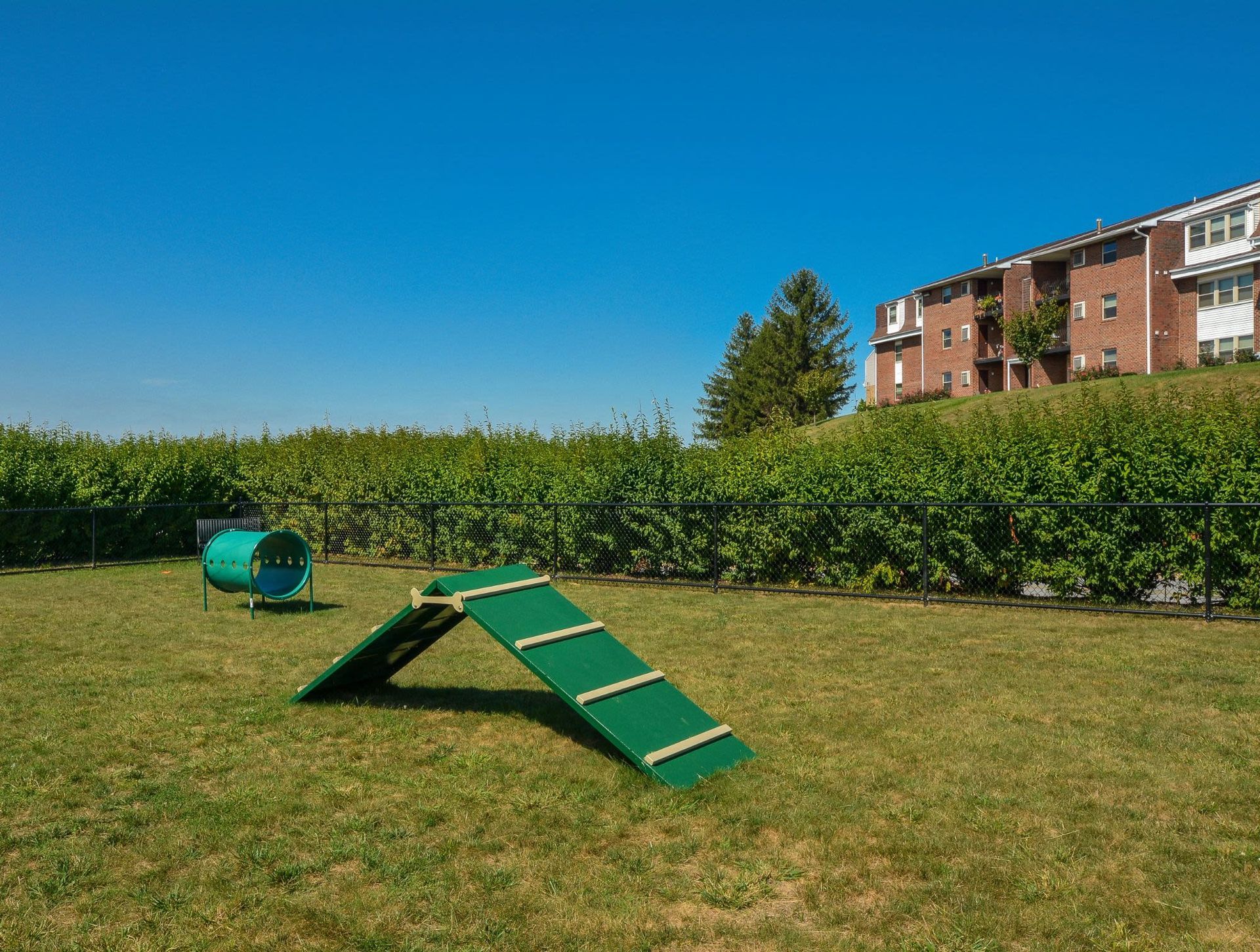 Playground on a grassy lawn with a brick apartment building in the background.