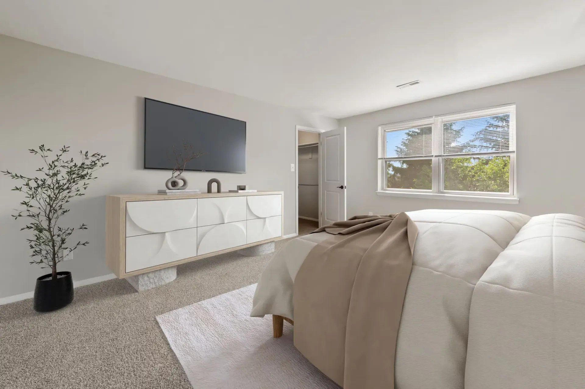 Bedroom with a large window, beige bedding, TV on the wall, and a decorative dresser.