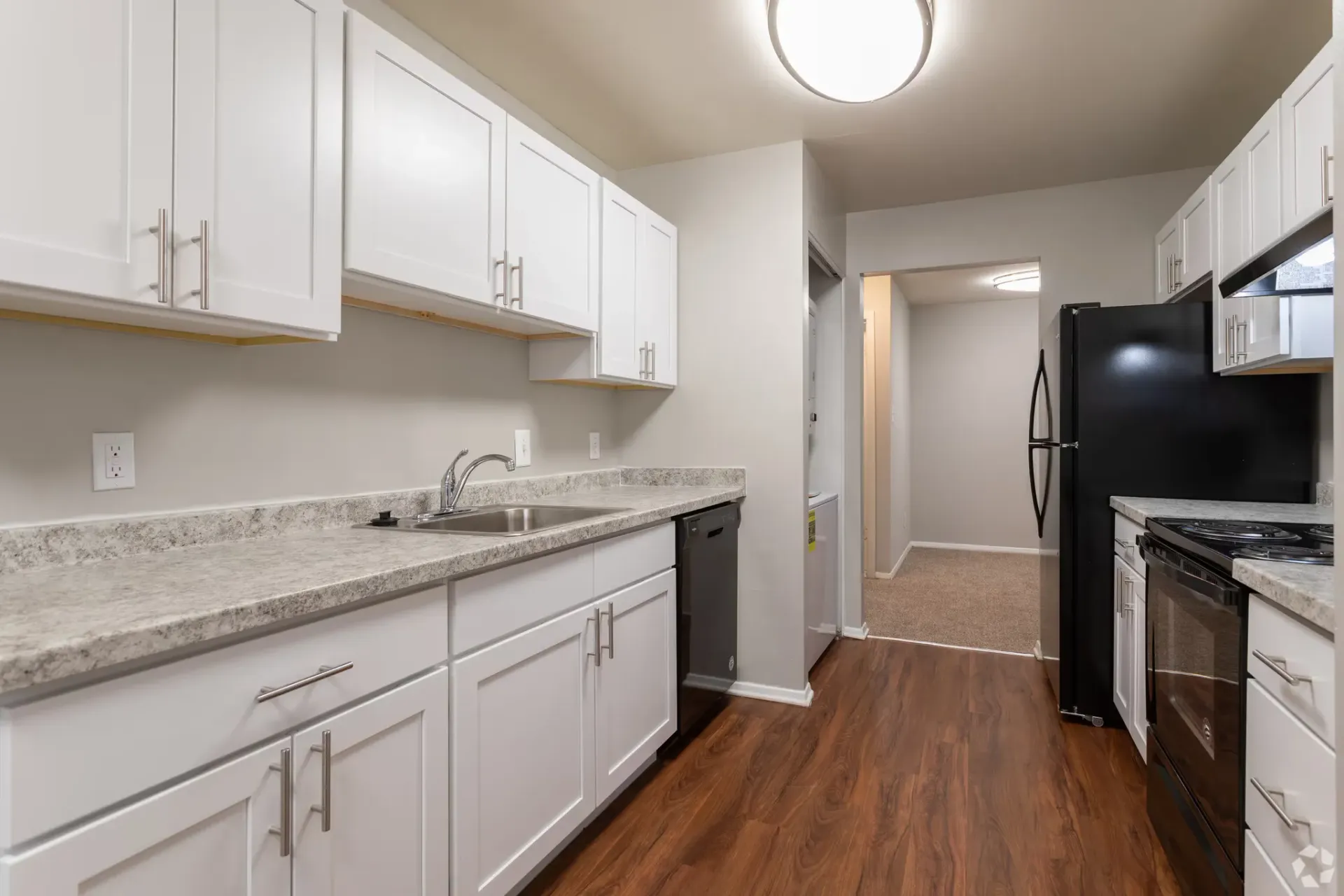 Kitchen with white upper and lower cabinets, grey speckled countertops, and stainless steel appliances.