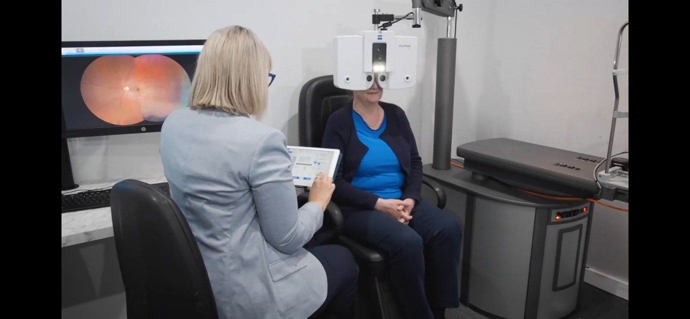 A woman is looking through a microscope at another woman 's eye.