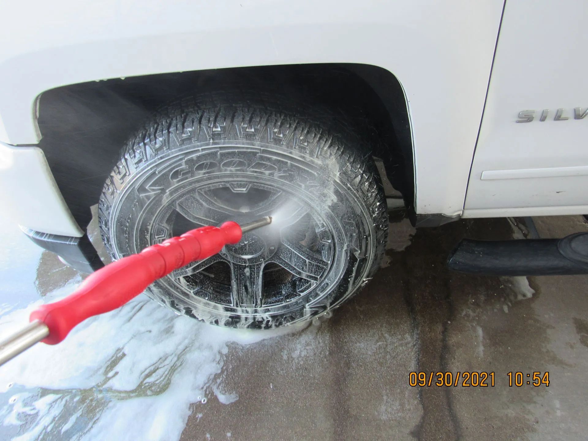 A white suv is being cleaned with a high pressure washer