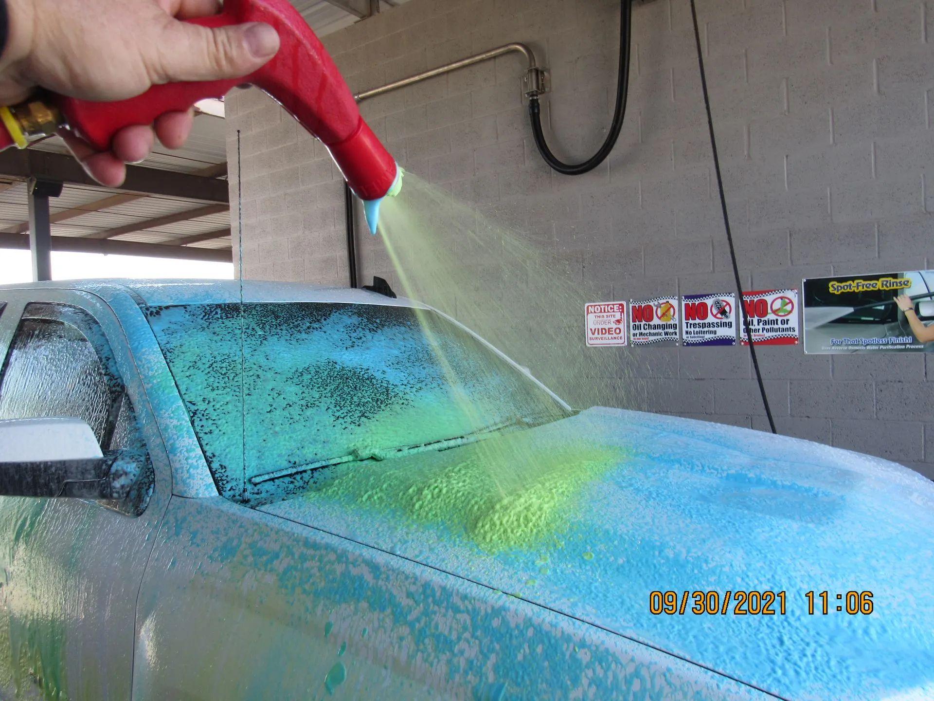 A person is spraying green paint on a blue car