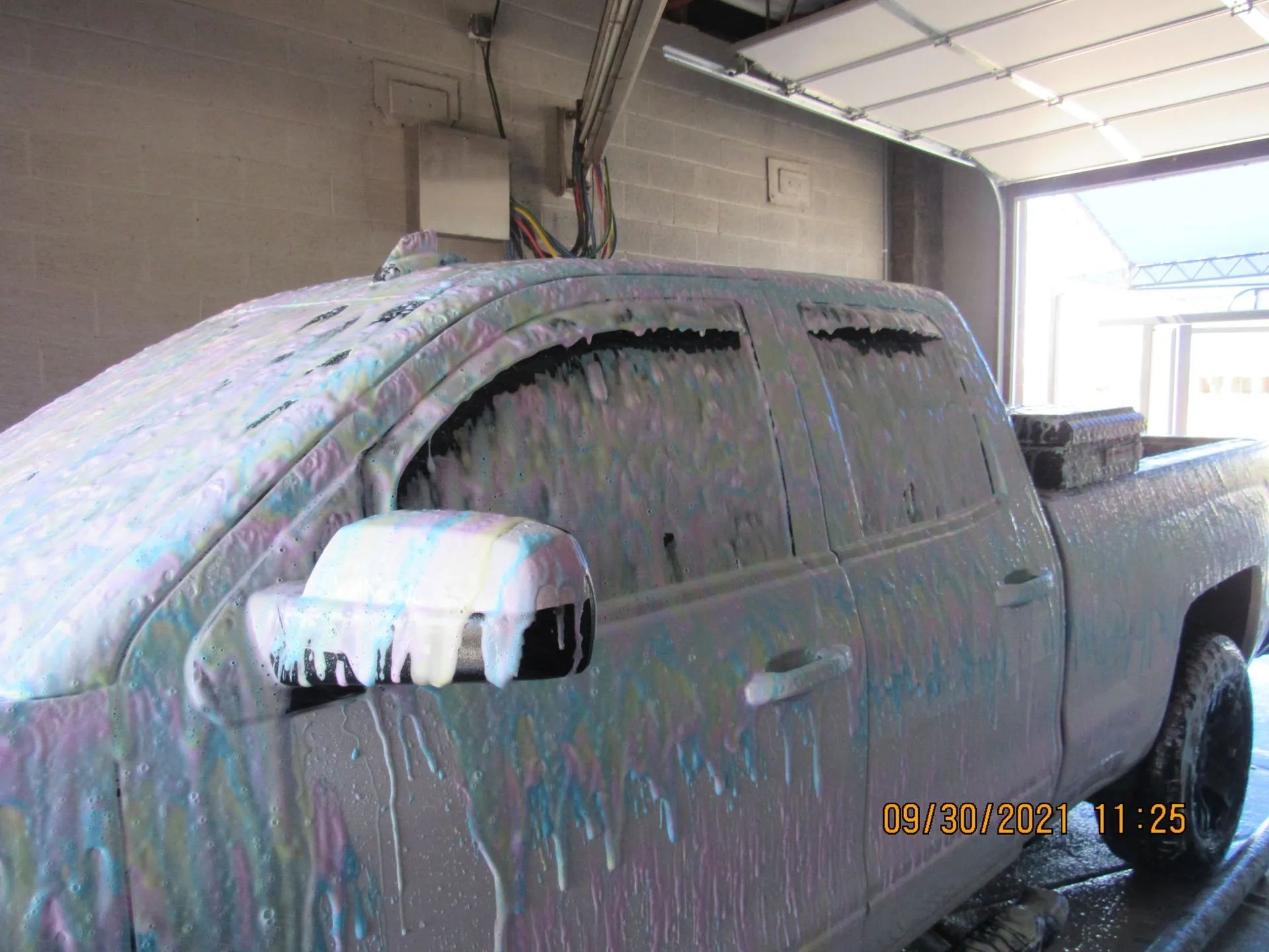 A truck is covered in foam in a garage.