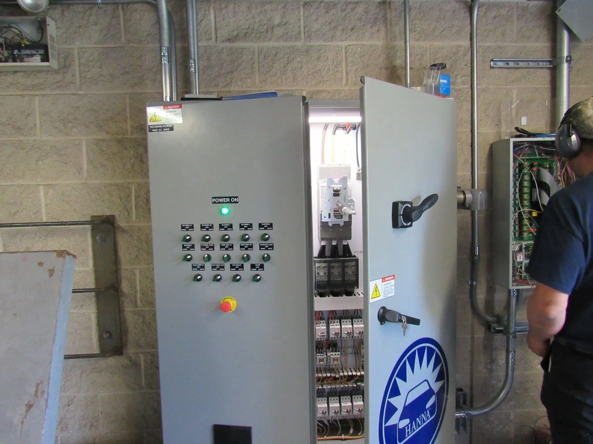A man is standing in front of a large electrical box with a sun logo on it