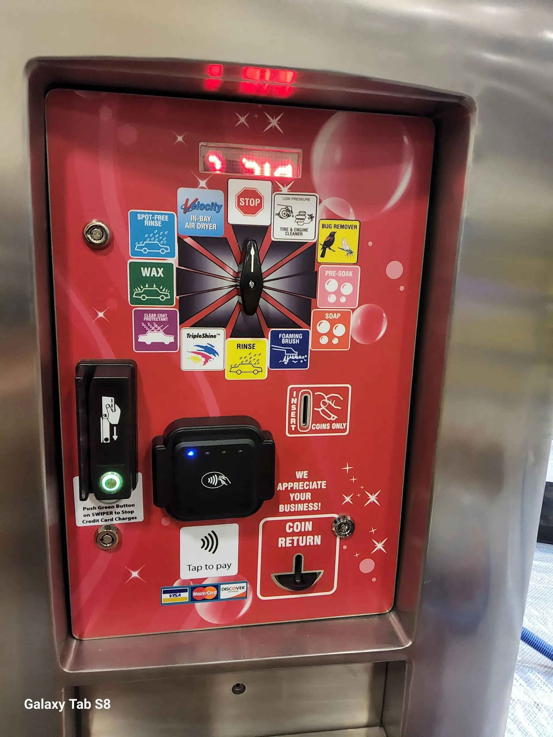 A red and stainless steel vending machine with stickers on it