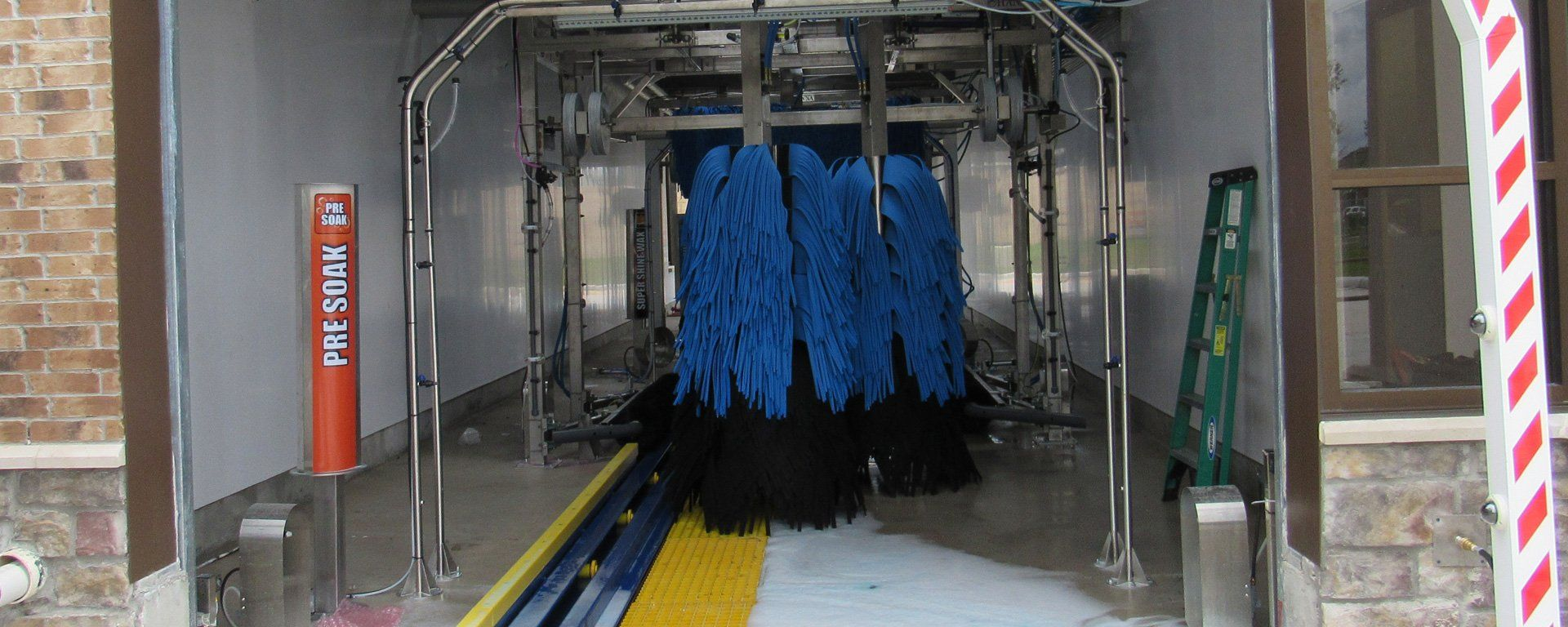 A car wash with blue brushes and foam coming out of it.