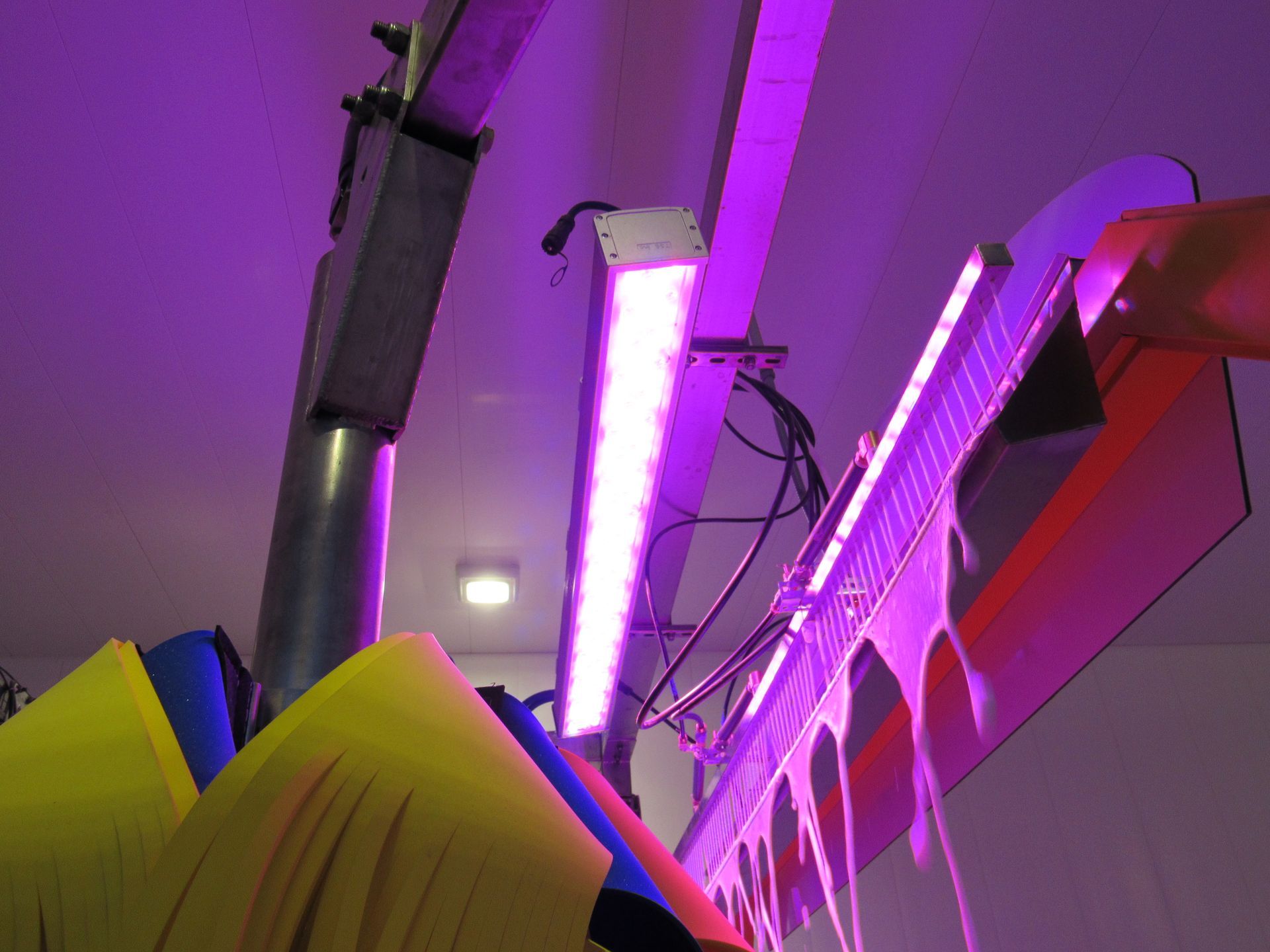 Purple neon light illuminating a car wash brush mechanism with yellow and blue flaps.