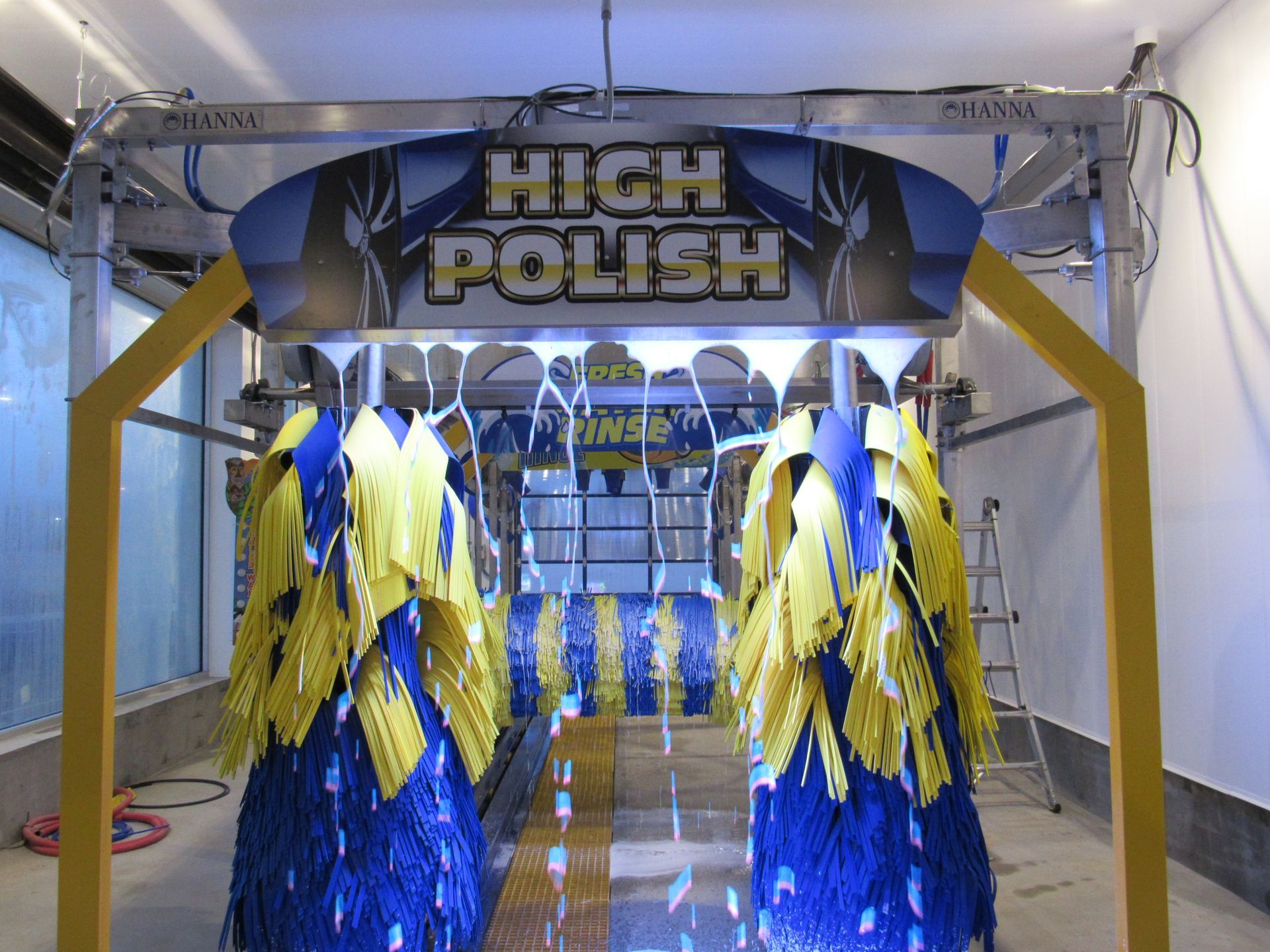 A car wash tunnel with yellow and blue brushes and a 