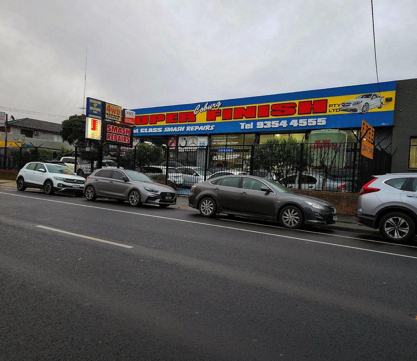 Blue BMW sedan with black wheels parked on a road, trees in the background.