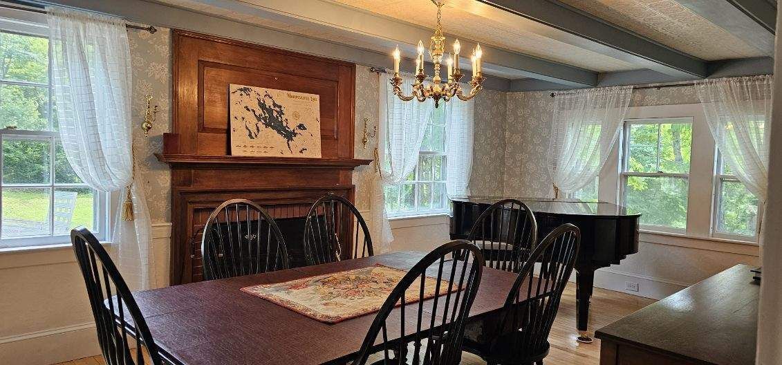 A dining room with a table and chairs and a piano.