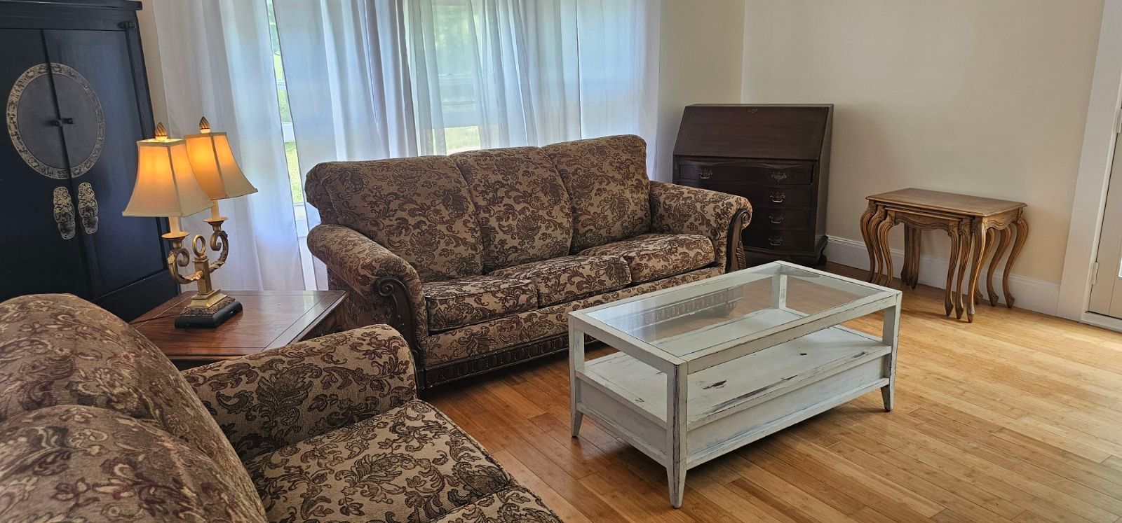 A living room with a couch , chair , coffee table and lamps.