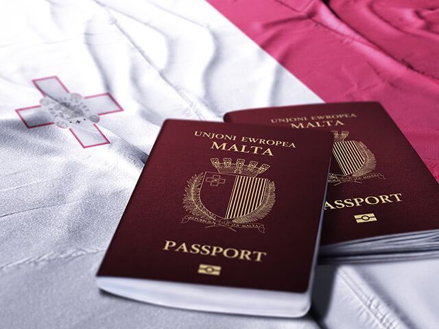 Two malta passports are sitting on top of a malta flag