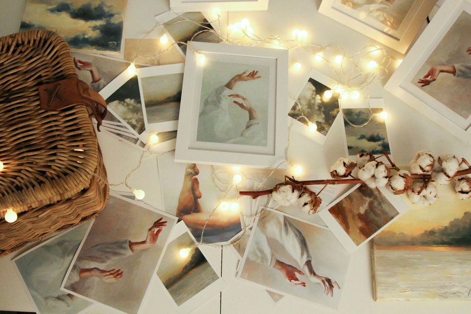 Des reproductions d'art et un tableau encadré, agencés avec des guirlandes lumineuses, un brin de coton et un panier en osier.