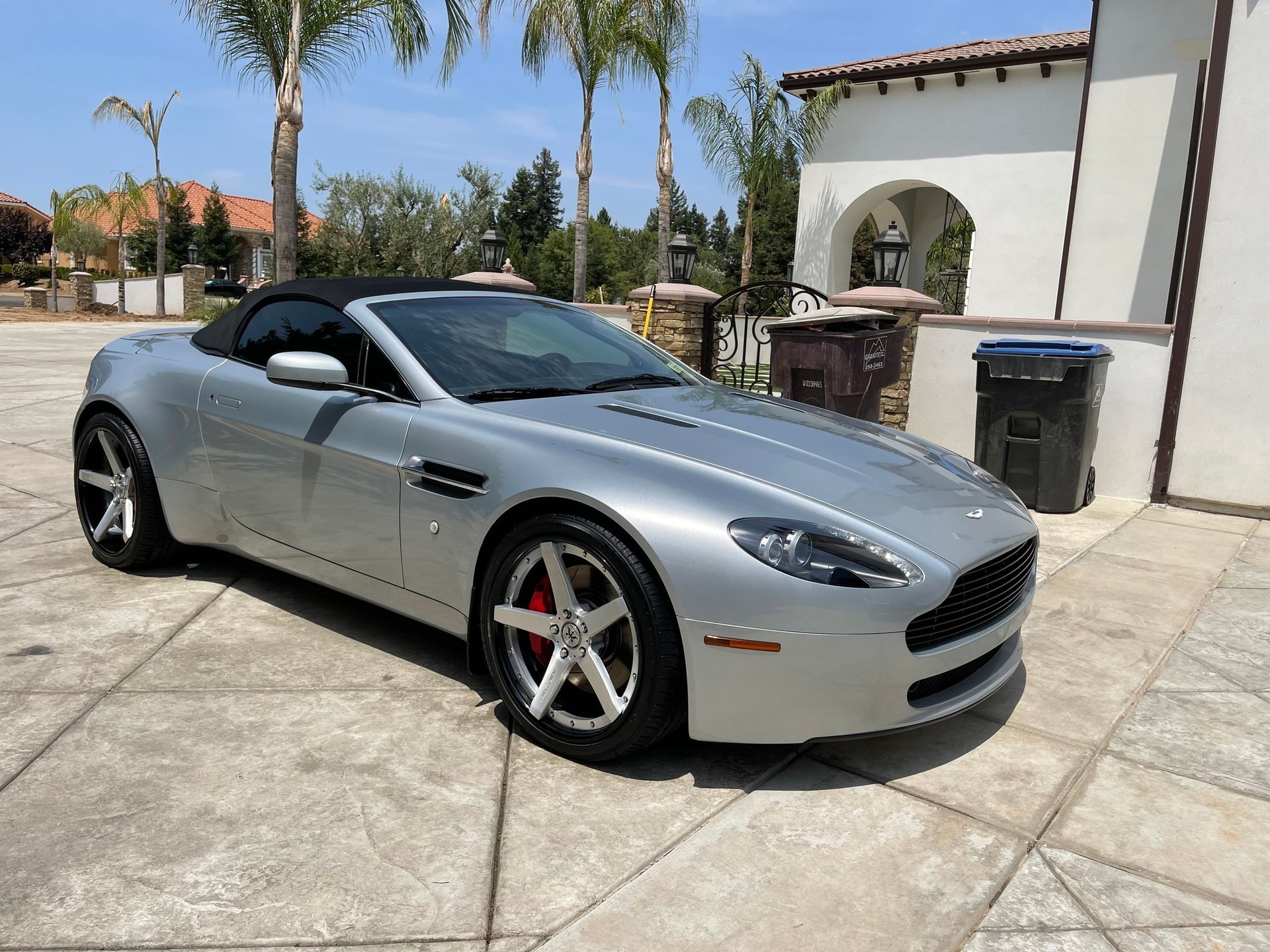 A silver sports car is parked in a driveway in front of a building.