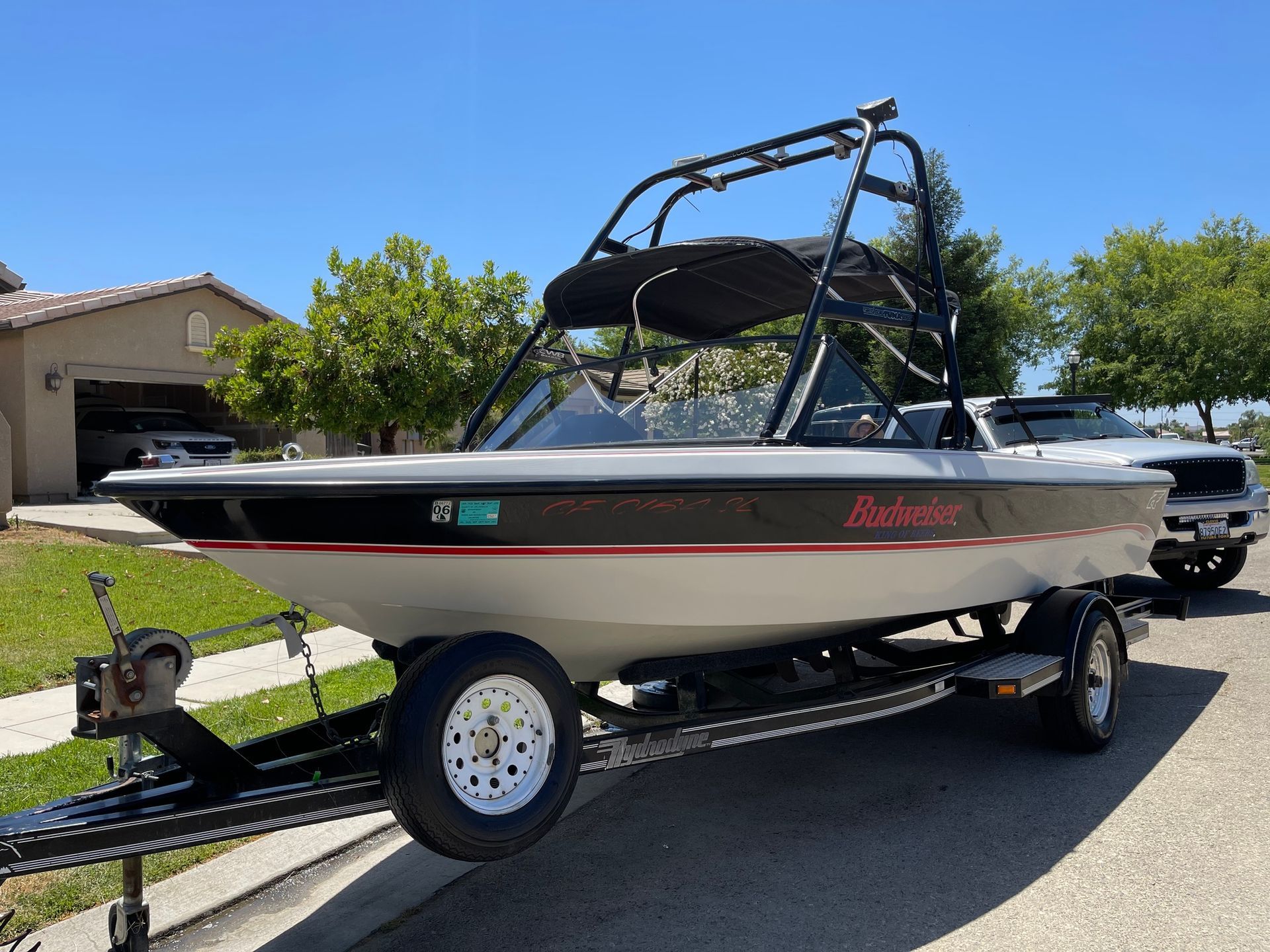 A boat is parked on the side of the road on a trailer.