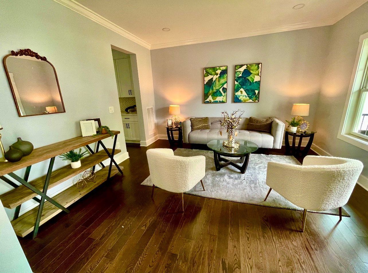 A living room with a couch , chairs , a coffee table and a mirror.