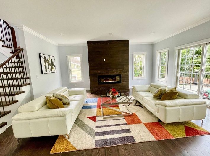 A living room with two couches , a fireplace , and a rug.