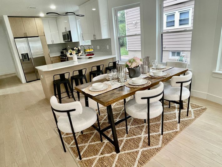 A dining room with a table and chairs and a rug.