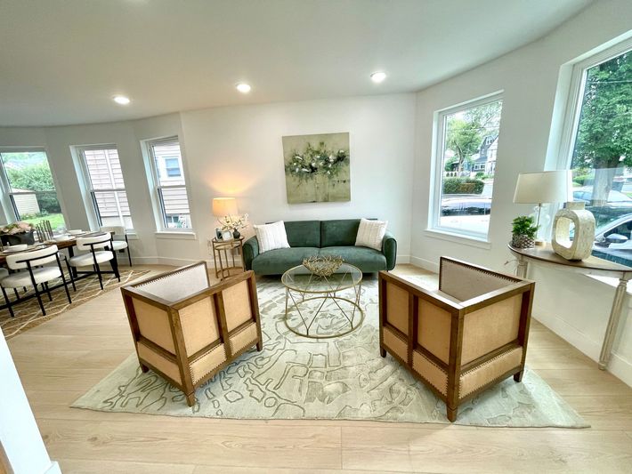 A living room with a green couch and two chairs.