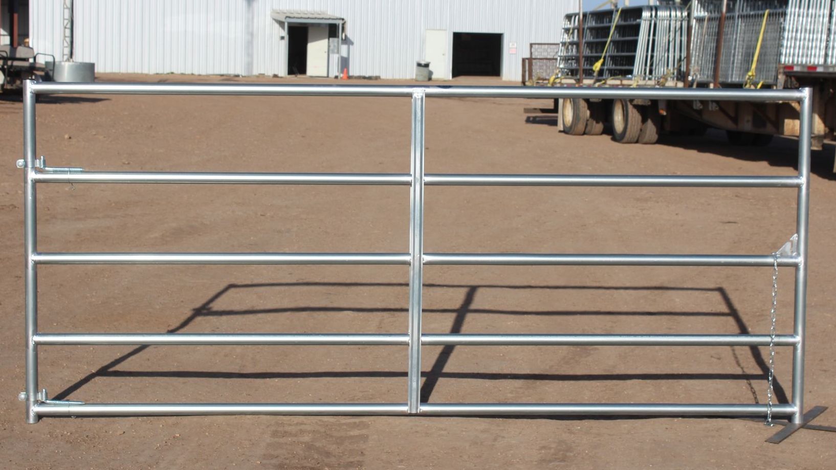 A metal gate is sitting in the dirt in front of a building