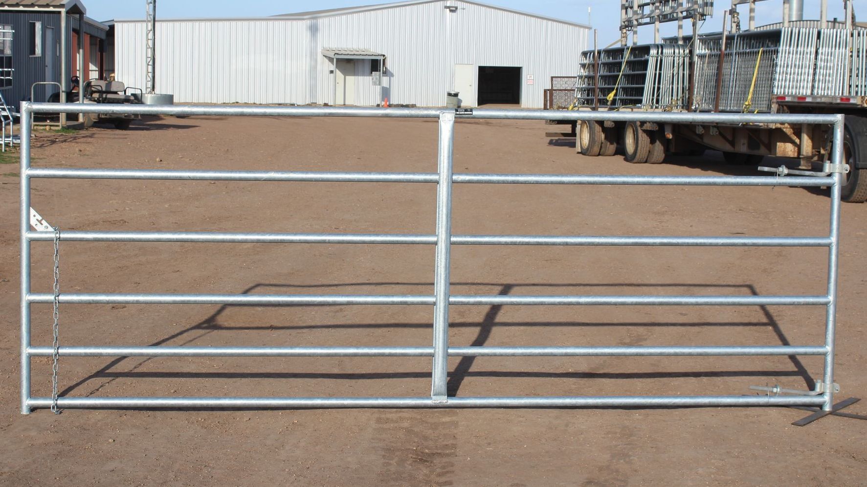 A metal gate is sitting in the dirt in front of a building