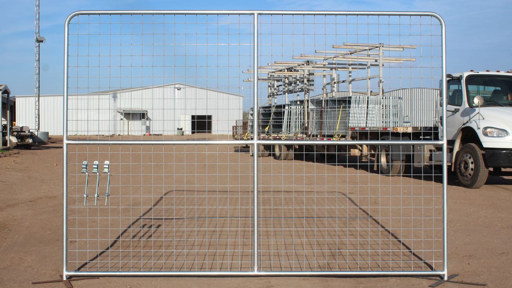 A truck is parked in front of a fence with a building in the background.
