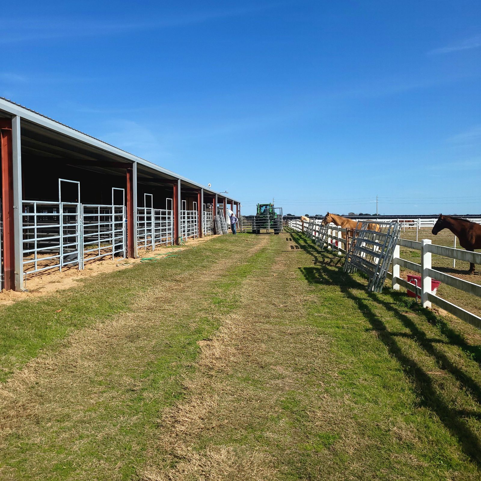 A row of horse stables with a tractor in the background.